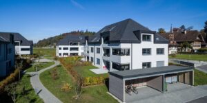 Aussenansicht einer Wohnüberbauung in Kiesen in Bern, deren Dächer mit Flachschiebeziegeln von Gasser Ceramic eingedeckt sind.