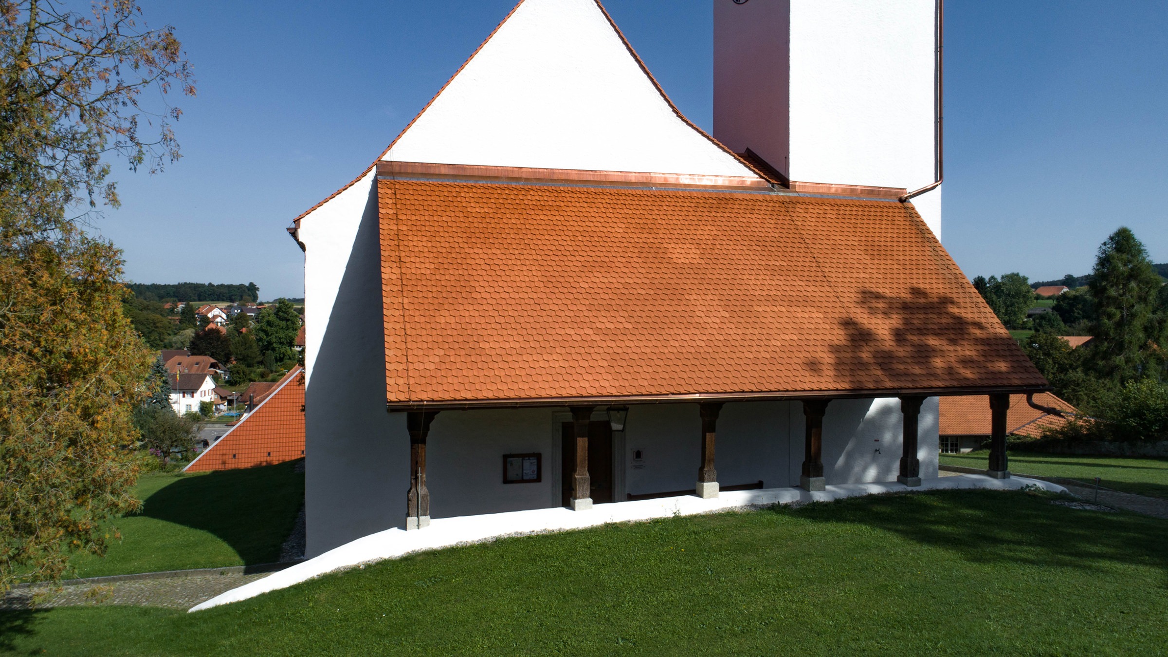 Drohnenaufnahme der Kirche Oberwil, die mit 24'400 Stück Biberschwanzziegel Berner Biber, spitz, naturrot von Gasser Ceramic eingedeckt ist.